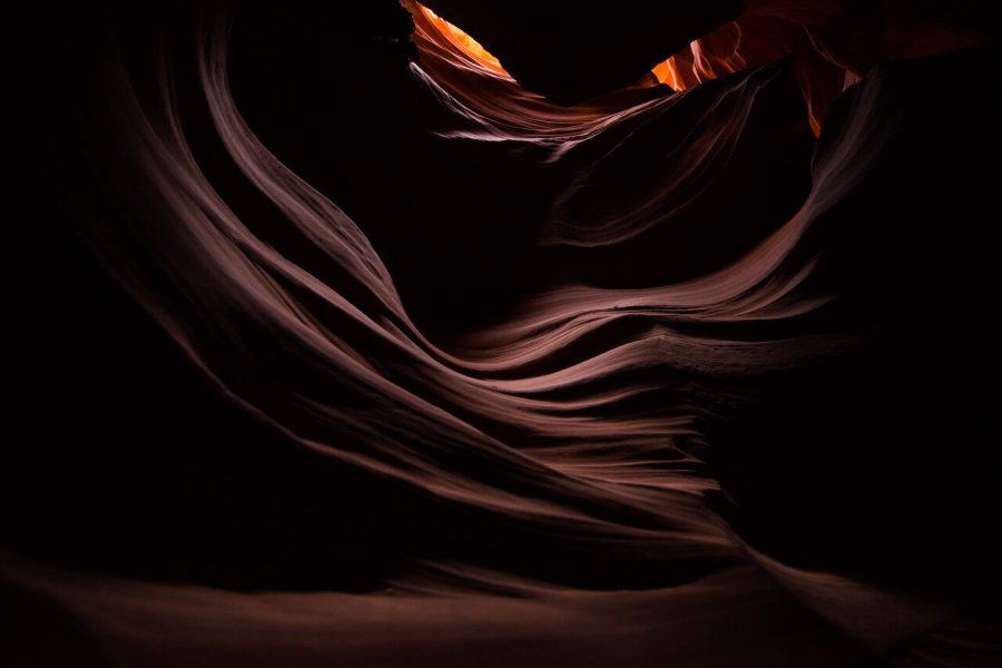 Curved sandstone walls with layered texture and a warm opening of light in Antelope Canyon