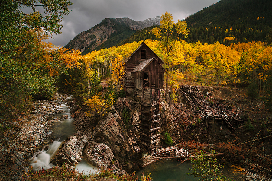Wooden cabin beside stream and autumn trees