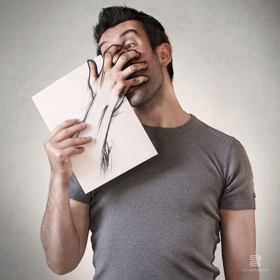 Artist holds a drawing across his face