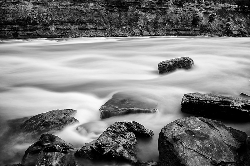Water flowing past rocks in monochrome