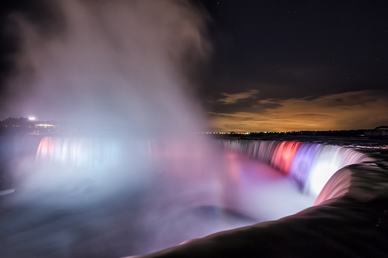 Niagara Falls lit in color through mist at night