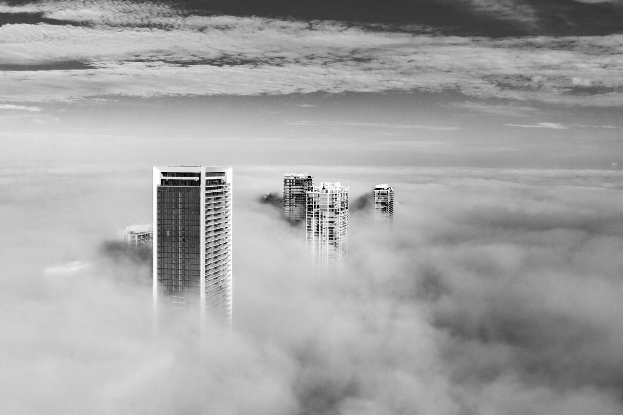 Black and white photograph of Miami towers rising above a sea of fog under layered clouds
