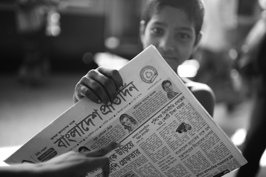 Child holding a newspaper near railway tracks