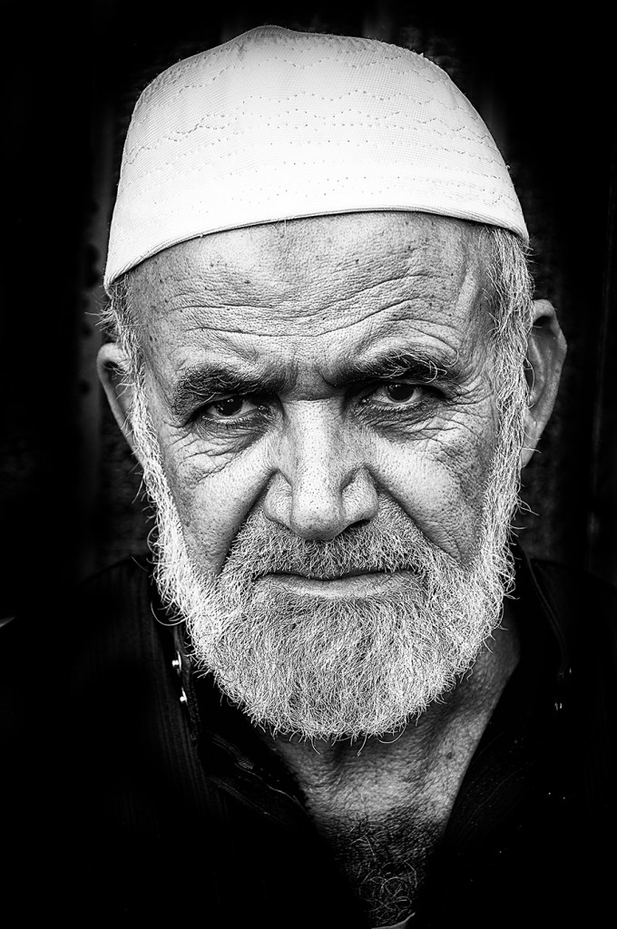 Black-and-white portrait of a bearded man in white cap