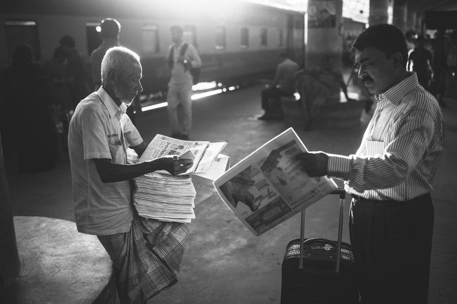 Men reading newspapers on a railway platform