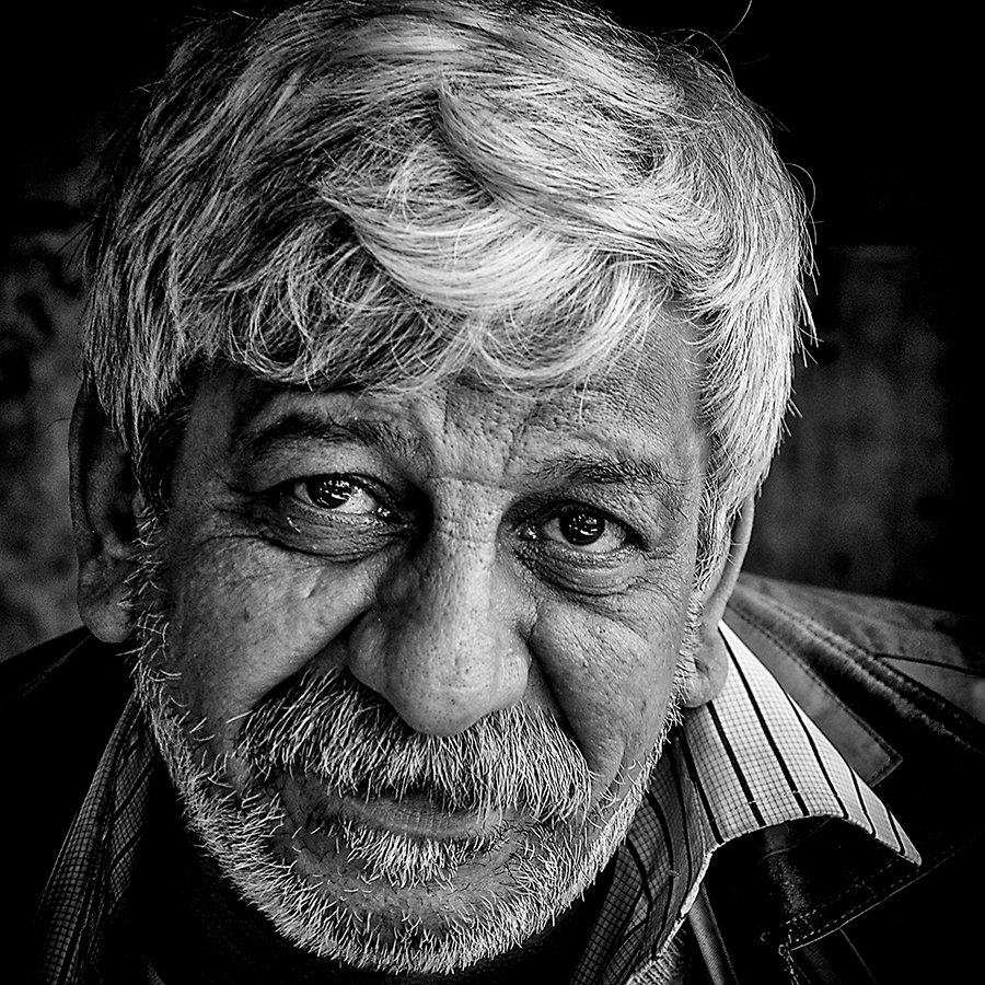 Close black-and-white portrait of an older bearded man