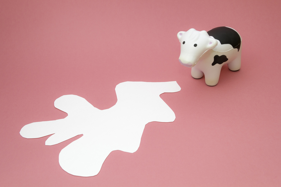 Small figure beside a white cut-paper shape on pink