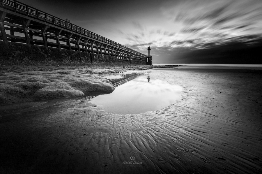 Pier and shore at low tide in monochrome