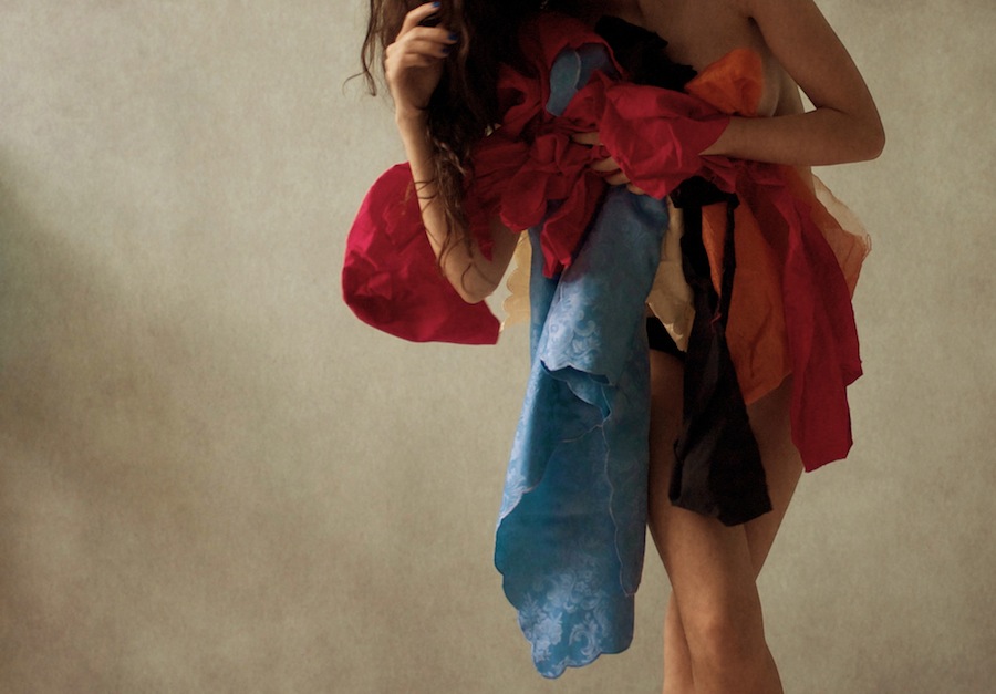 Figure holding colorful fabric against muted backdrop