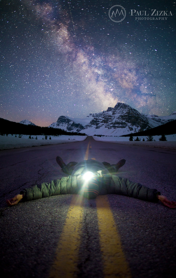 Photographer under a starry sky beside a lake