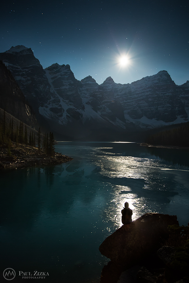 Figure beside a lake beneath a moonlit ridge