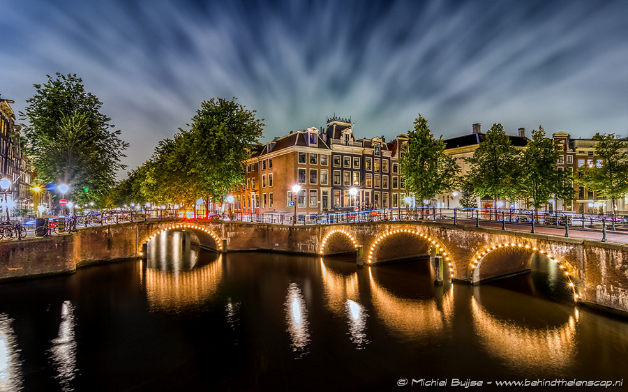 Lit Amsterdam canal bridge after dark