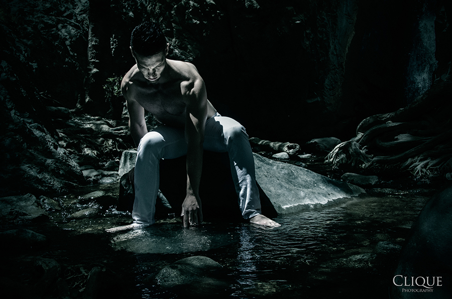 Figure seated among rocks and water