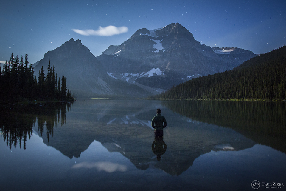 Figure beside an alpine lake and mountains