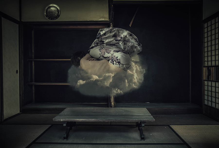Woman in a floating pose inside a dark room