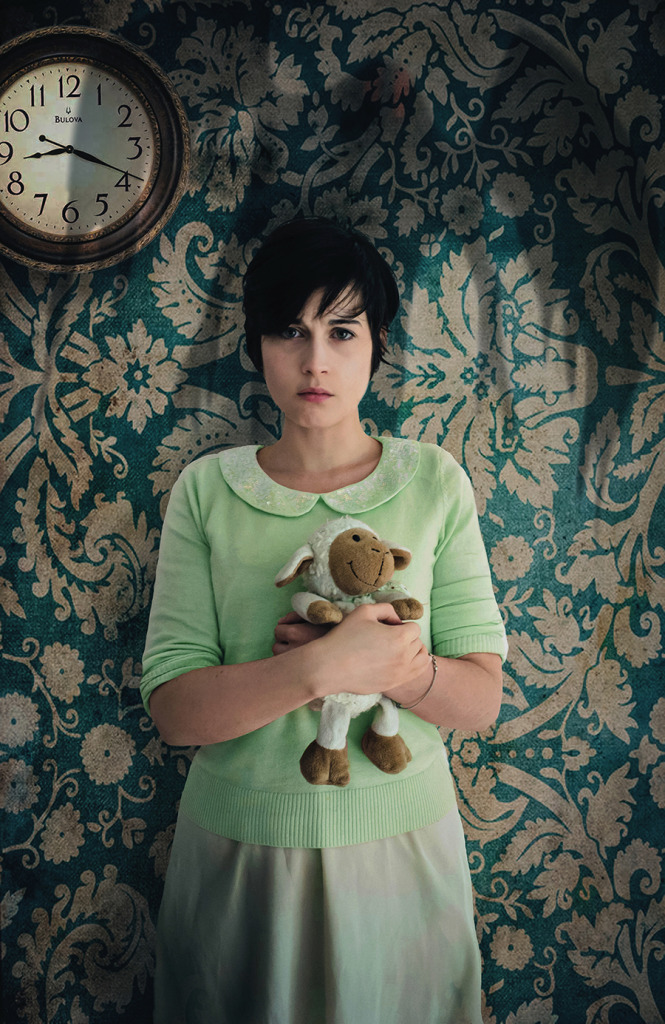 Woman holding flowers against patterned wall