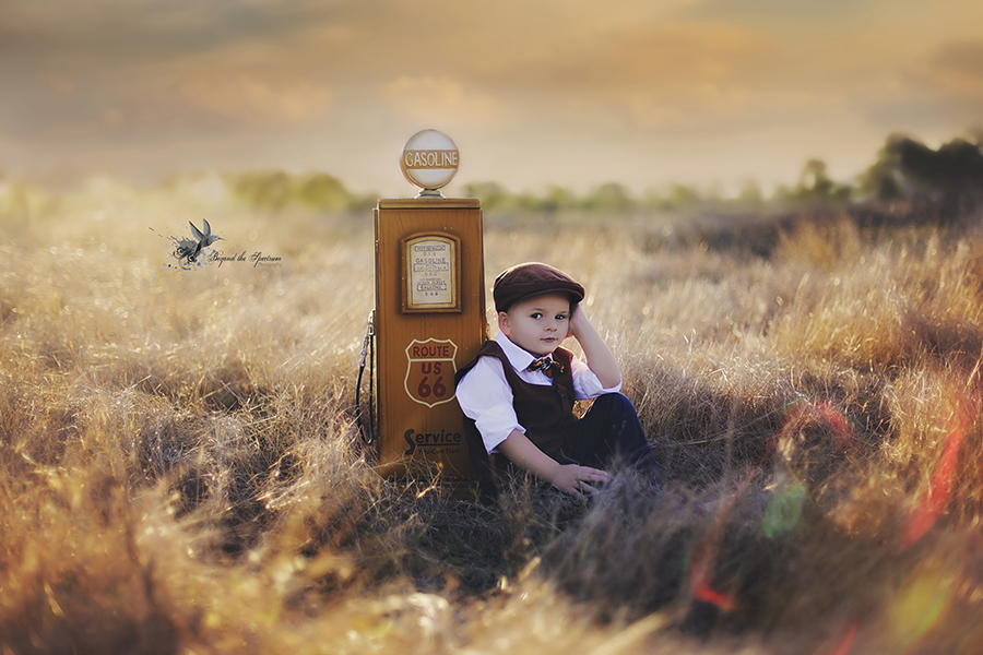 Child next to a vintage fuel pump in a field