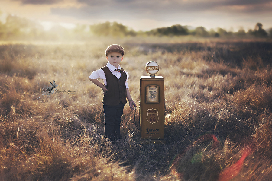 Child in a field next to a vintage fuel pump
