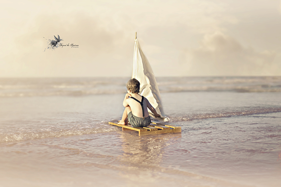 Child beside a small sailboat in shallow water