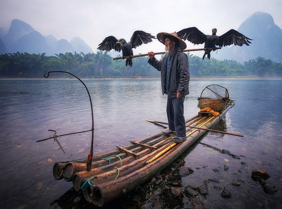 Cormorant fisherman standing on a boat