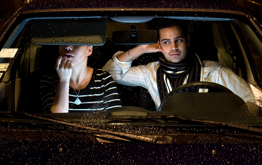 Passengers seen through a rain-speckled windshield