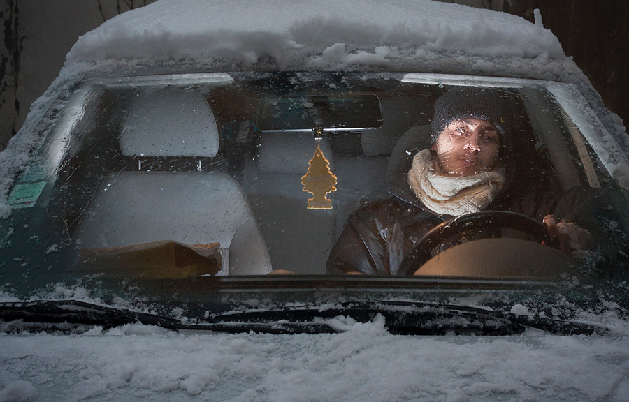 Person alone in a snow-covered car