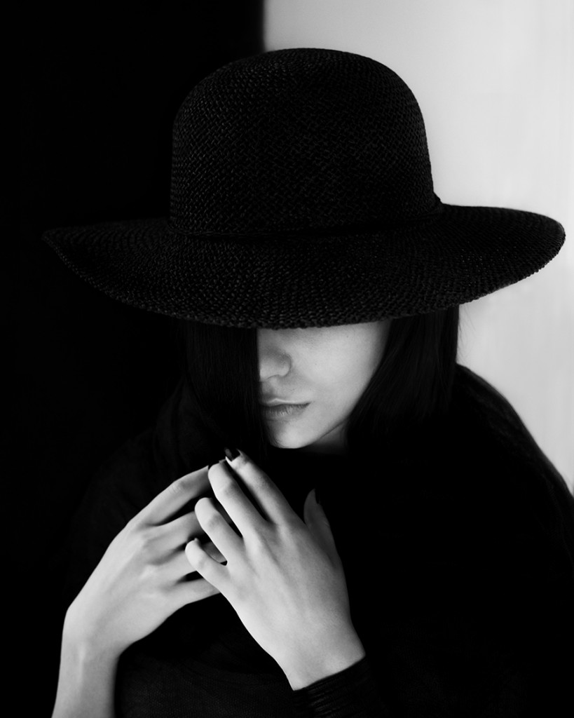 Woman in black hat holding her hands near her face