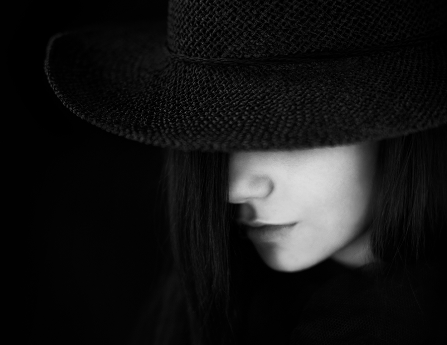 Profile of woman in black hat against dark background