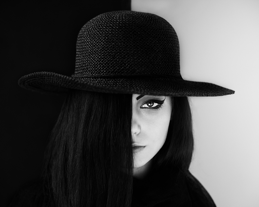 Woman in black hat half hidden by shadow