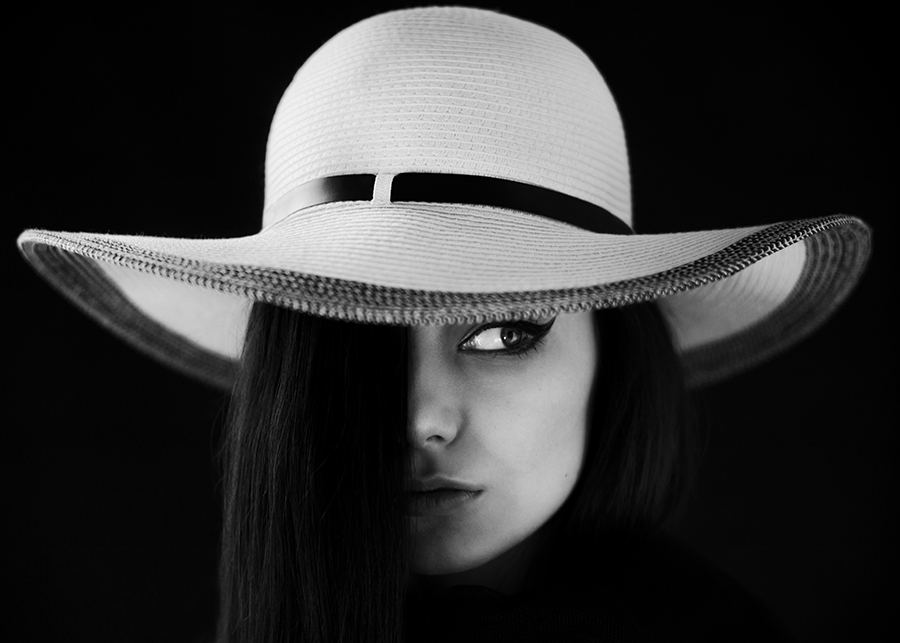 Woman in white hat with face divided by shadow