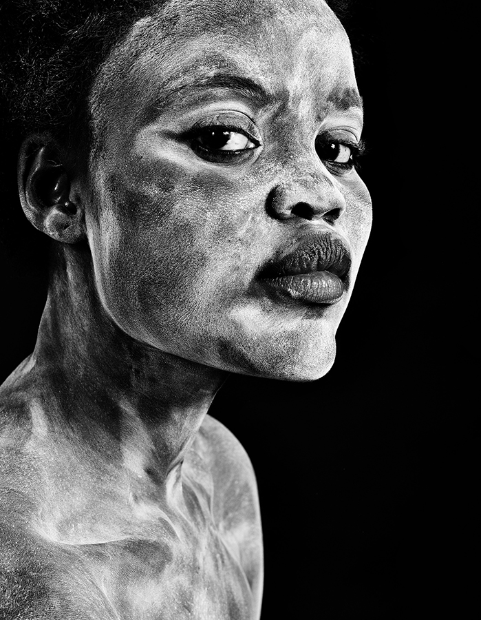 Black-and-white portrait of a woman with clay on her face