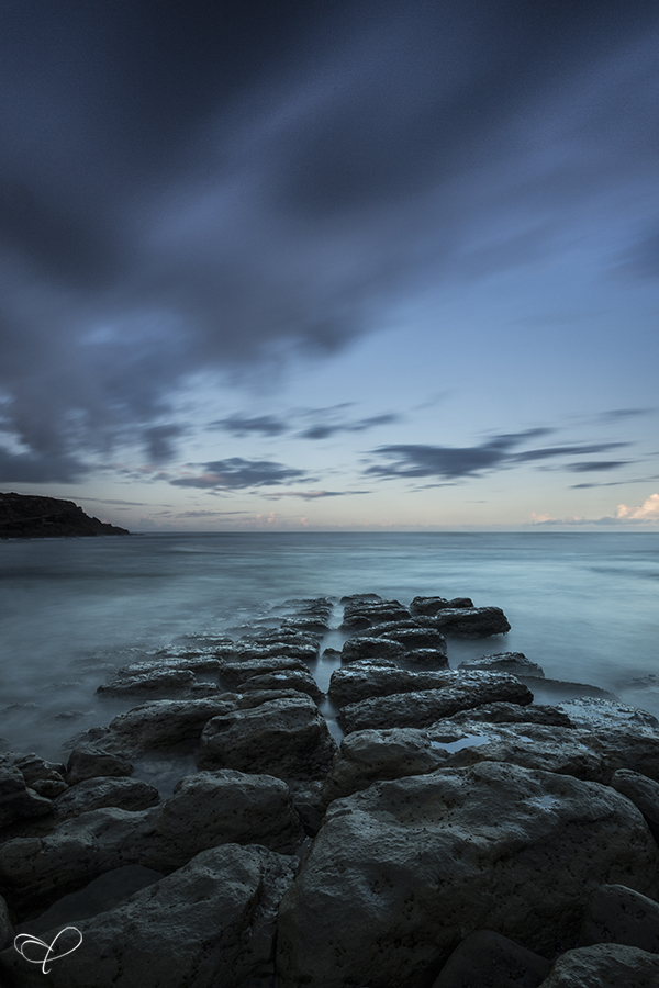 Rocky shoreline beneath blue-grey clouds