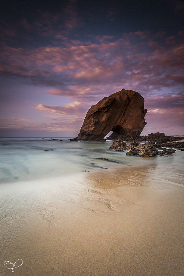 Rock on a beach under a purple sky