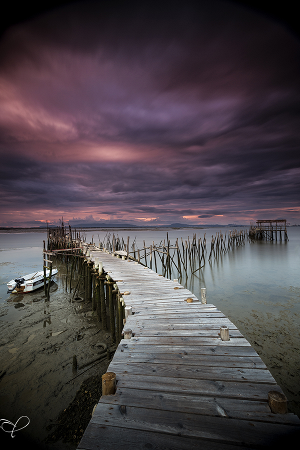 Wooden pier over water beneath a purple sky