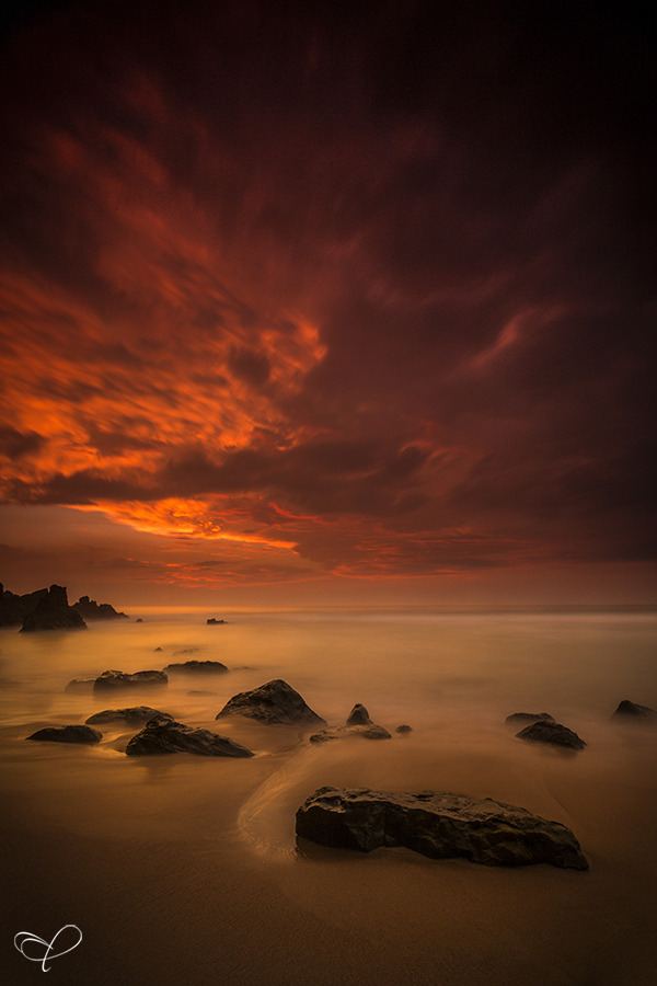 Orange sunset over scattered coastal rocks