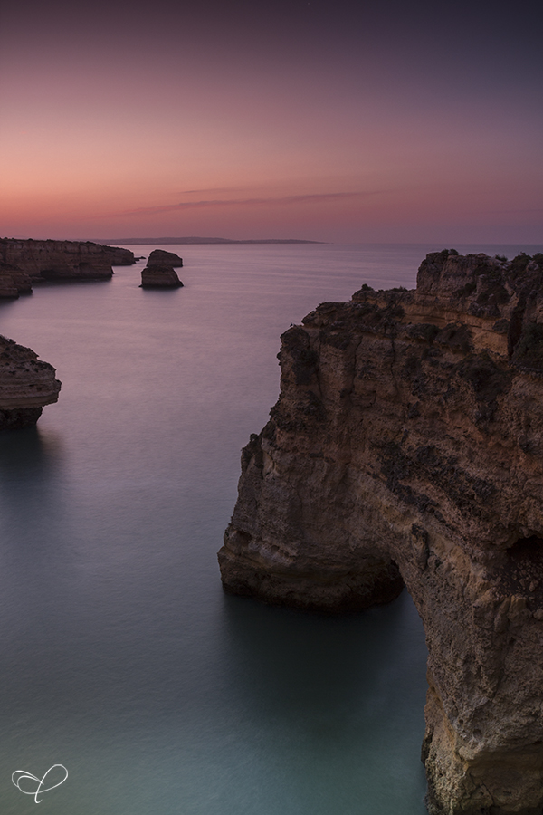Rock formation rising from sea at dusk