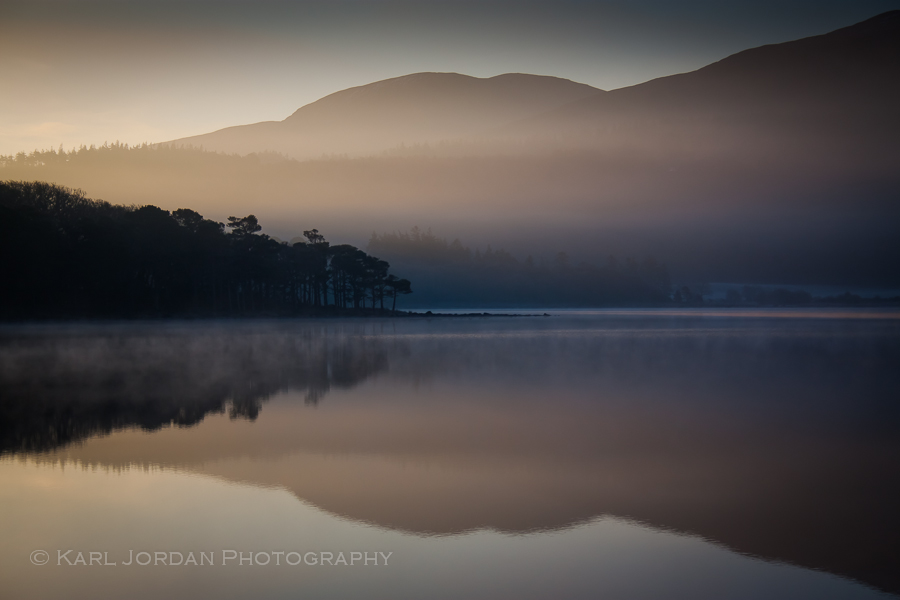 Blue morning light over mountains and reeds reflected on Killarney lake, County Kerry