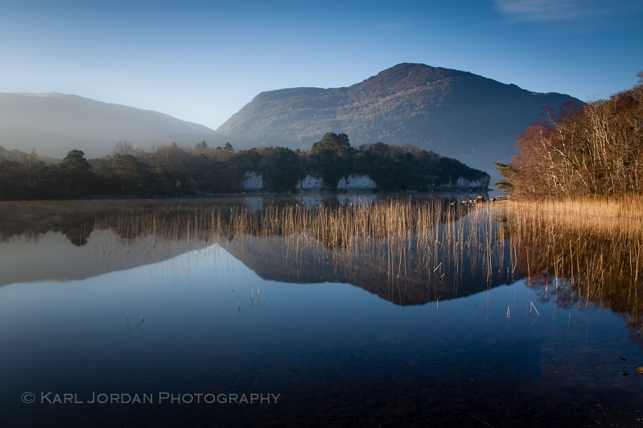 Mountain and reed bed reflected in calm blue water, Killarney National Park landscape photography