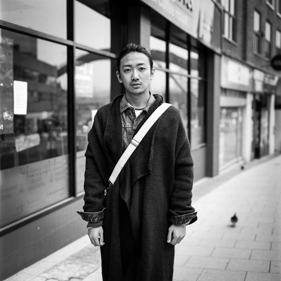 Person with shoulder bag beside shop windows