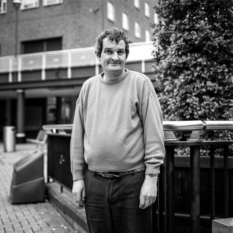 Black-and-white street portrait of a man by a railing
