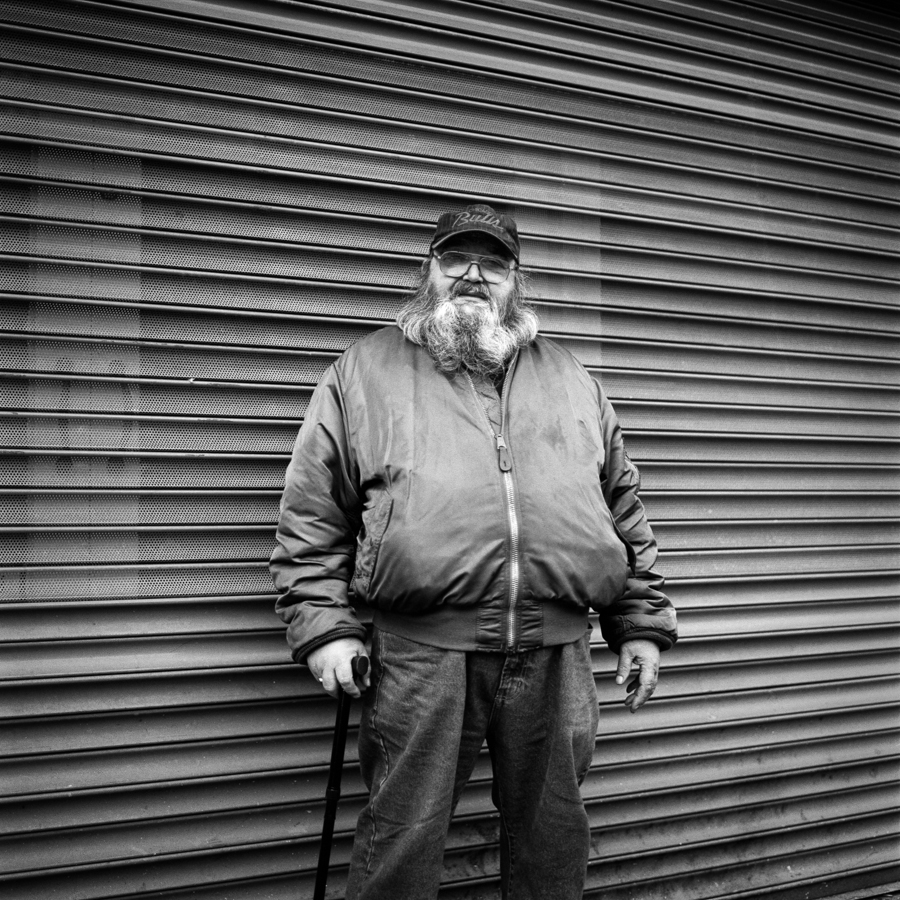 Bearded man in front of a shuttered shop