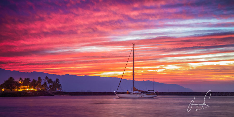 Sailboat silhouetted against a pink sunset
