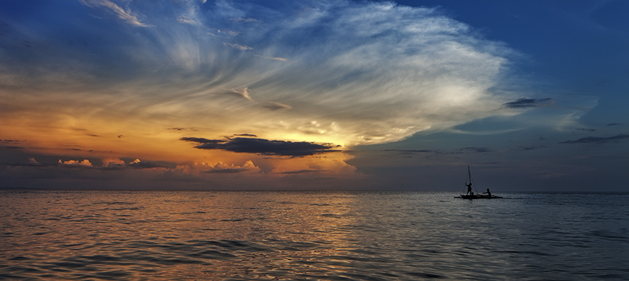 Boat under a dramatic sunset sky