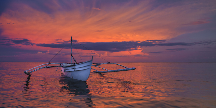 Boat silhouetted in a vivid orange sunset