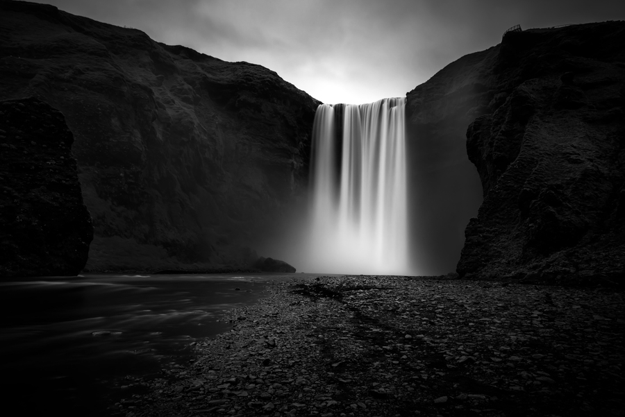 Black-and-white waterfall beneath cliffs