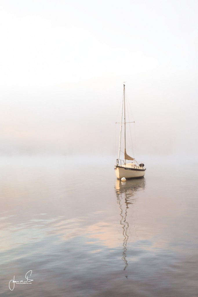 Single sailboat in misty water