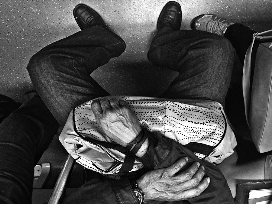 Passengers’ hands and a bag seen from above on a train