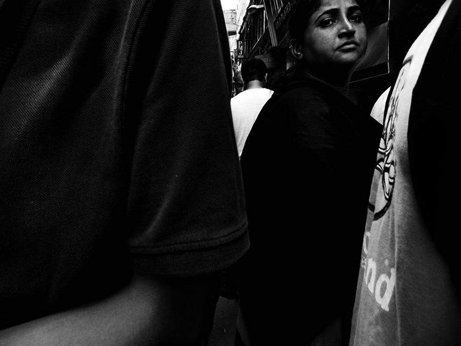 Woman visible between people in a street crowd