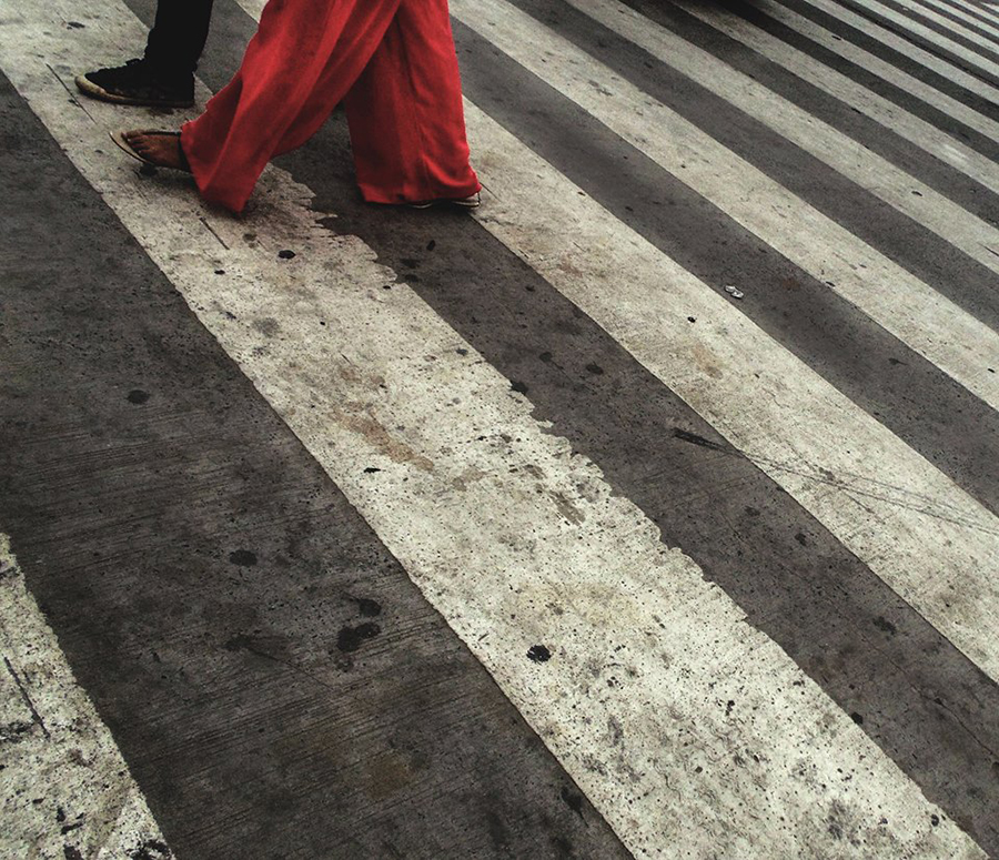 Person in red crossing a striped roadway