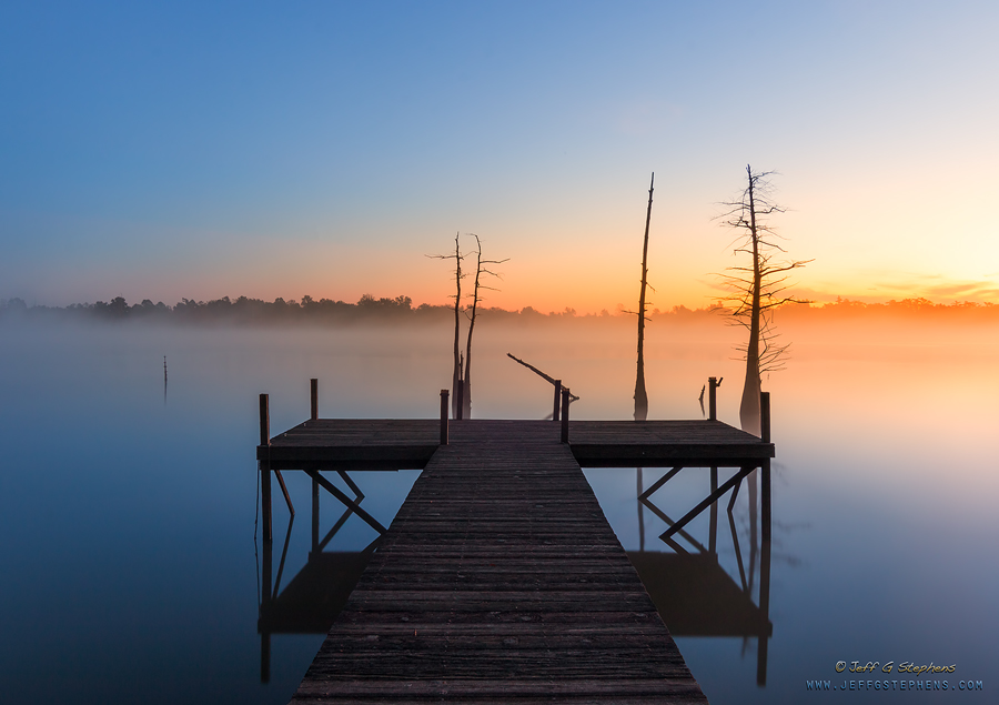 Dock reaching into the quiet lake at dawn